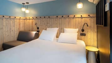 Ett hotellrum med en stor säng, en stol, ett litet bord och träpanel på väggarna.