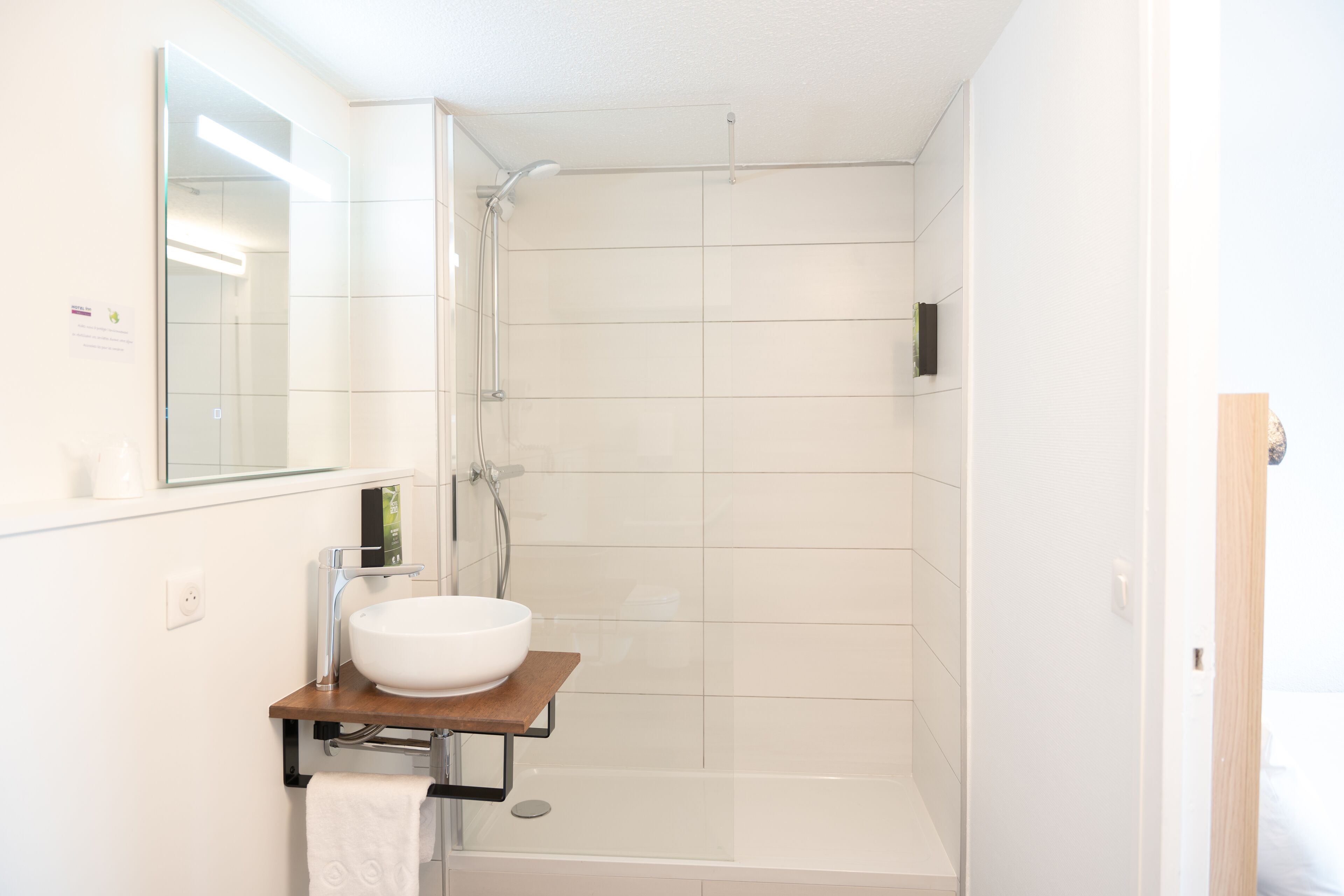 Une salle de bain moderne avec un lavabo blanc, un miroir et une douche.