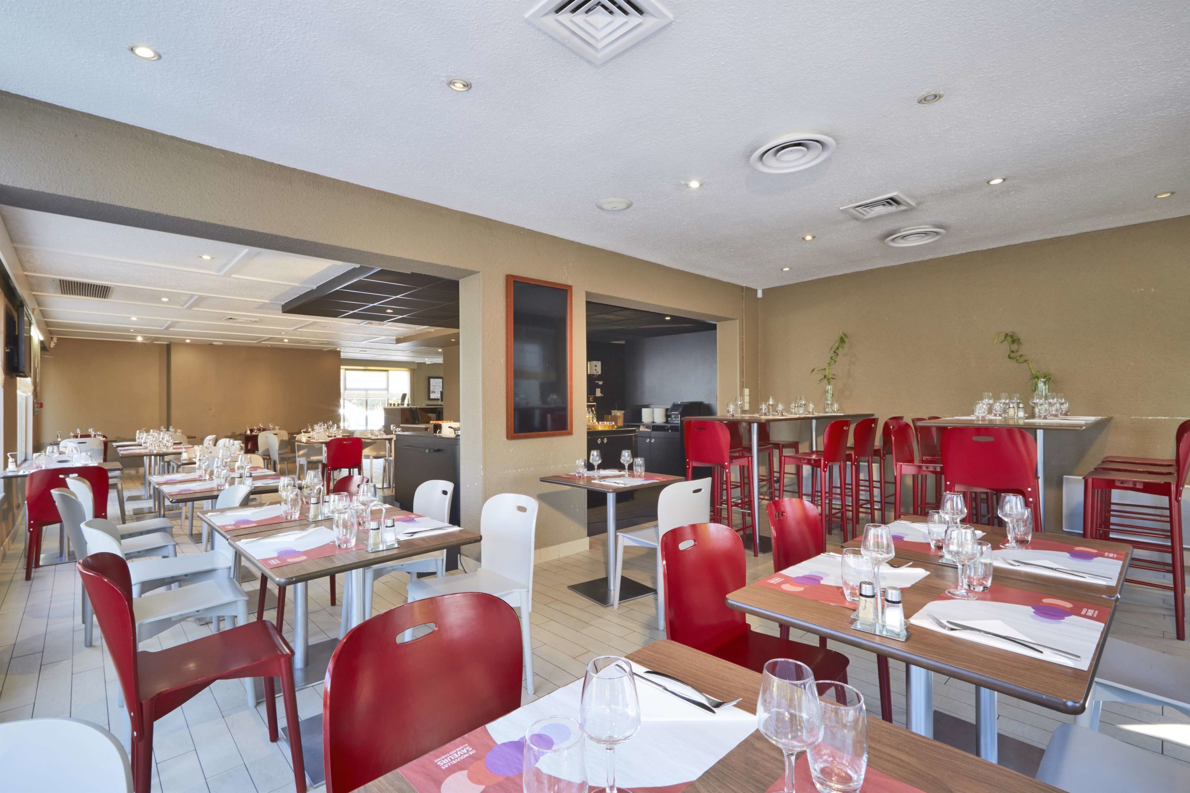 A restaurant with multiple tables and chairs, a kitchen area, and a view of the outdoors.