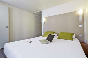 A hotel room with a bed, a laptop, and a green pillow. - Campanile Lyon Ecully (Ecully)