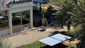 A restaurant with outdoor seating, a large umbrella, and a potted plant. - Campanile Lyon Ecully (Ecully)