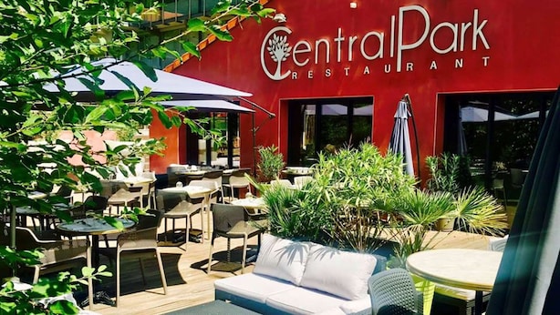 CentralPark Restaurant with outdoor seating, including wicker chairs and tables, surrounded by greenery. - Kyriad Lyon Sud Sainte Foy (Sainte-Foy-les-Lyon)