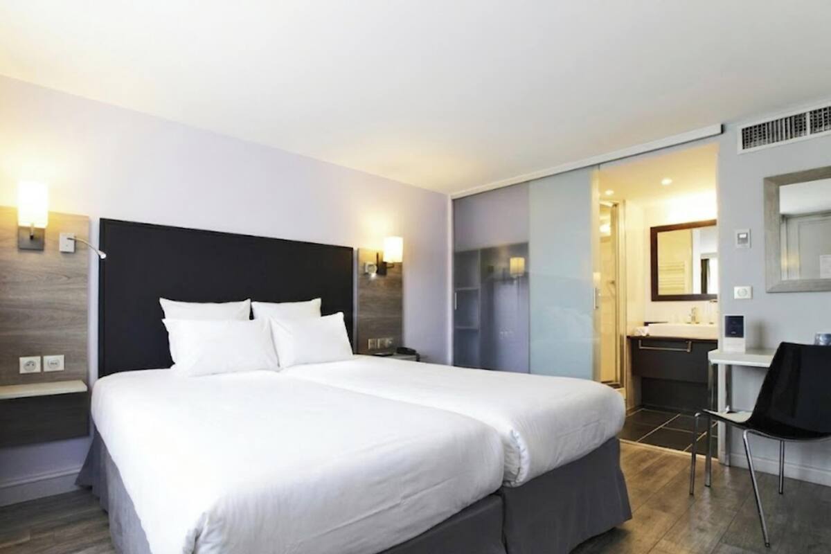 A modern hotel room with a large bed, bedside tables, a desk, and a chair.