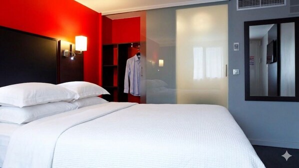 A hotel room with a bed, a wardrobe, and a mirror.