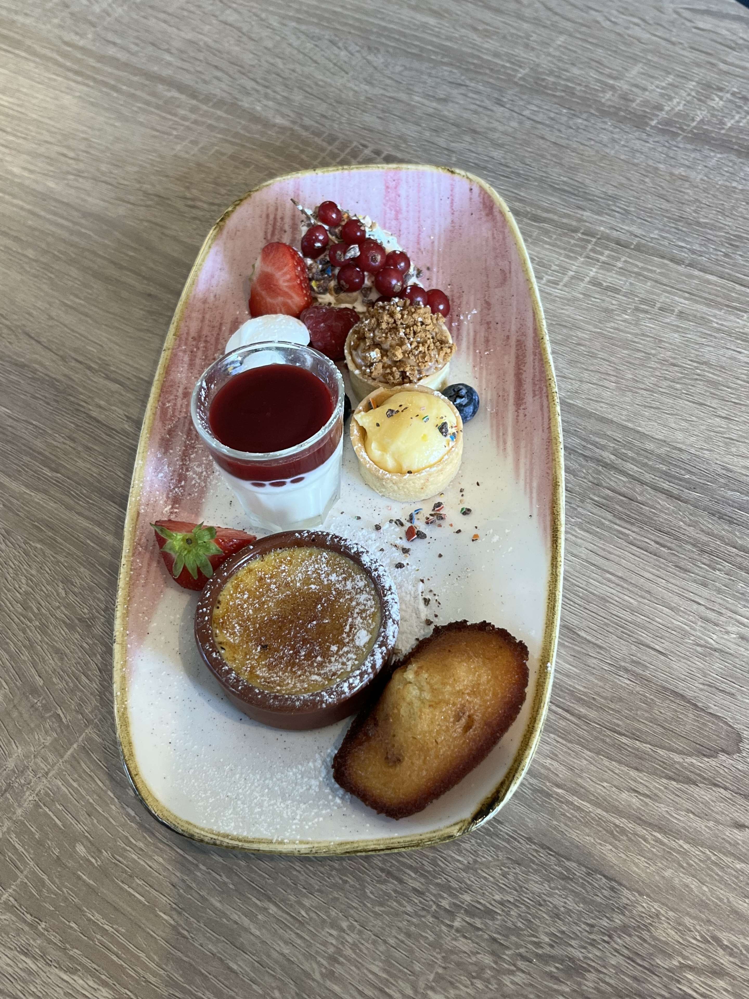 A dessert plate with various items including a custard, a berry compote, and a pastry.
