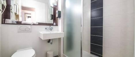 A bathroom with a toilet, sink, and glass shower enclosure.