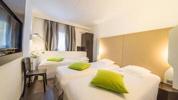 A hotel room with two beds, a desk, a chair, and a large mirror.