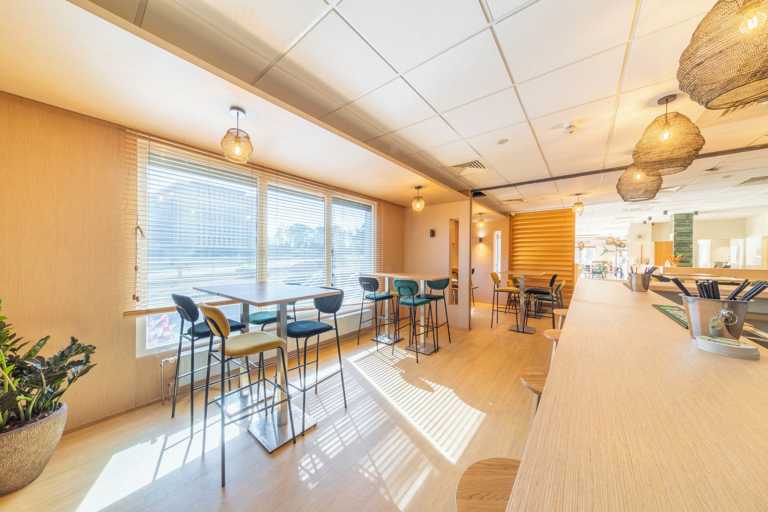 A modern bar area with wooden flooring, bar stools, and pendant lighting.
