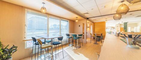 A modern bar area with wooden flooring, bar stools, and pendant lighting.