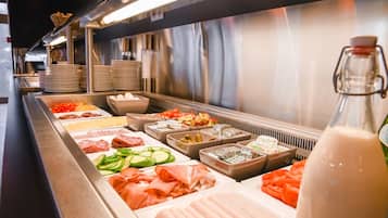 Un bufé con diversas opciones de comida, incluyendo carnes, quesos y verduras.