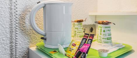 A kitchenette with a white coffee maker, Lipton tea packets, and a carton of fresh milk.