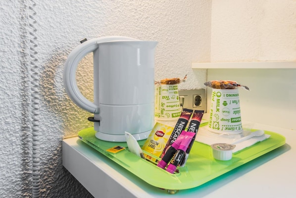A kitchenette with a white coffee maker, Lipton tea packets, and a carton of fresh milk.