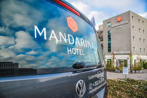 A vehicle with "MANDARINA HOTEL" and contact information for the Luxembourg Airport.