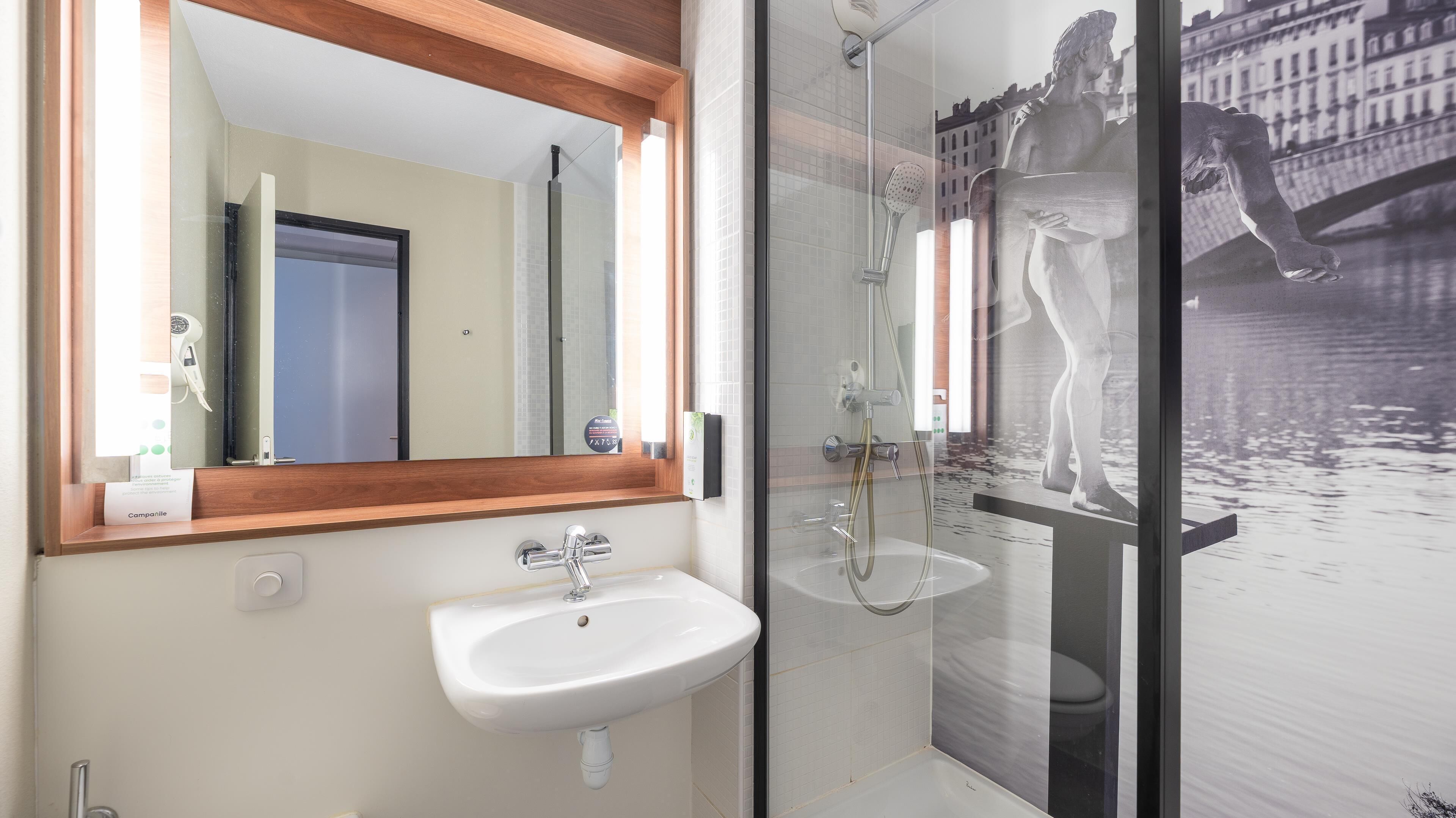 A modern bathroom with a white sink, a mirror, and a glass shower enclosure.