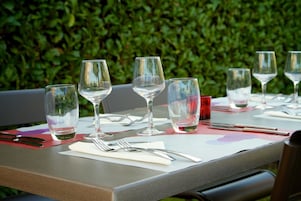 Una mesa lista para comer, con copas de vino, vasos de agua y cubiertos.