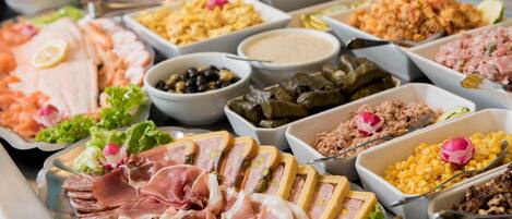 Un bufé con diversas opciones de comida, incluyendo carnes, ensaladas y salsas.