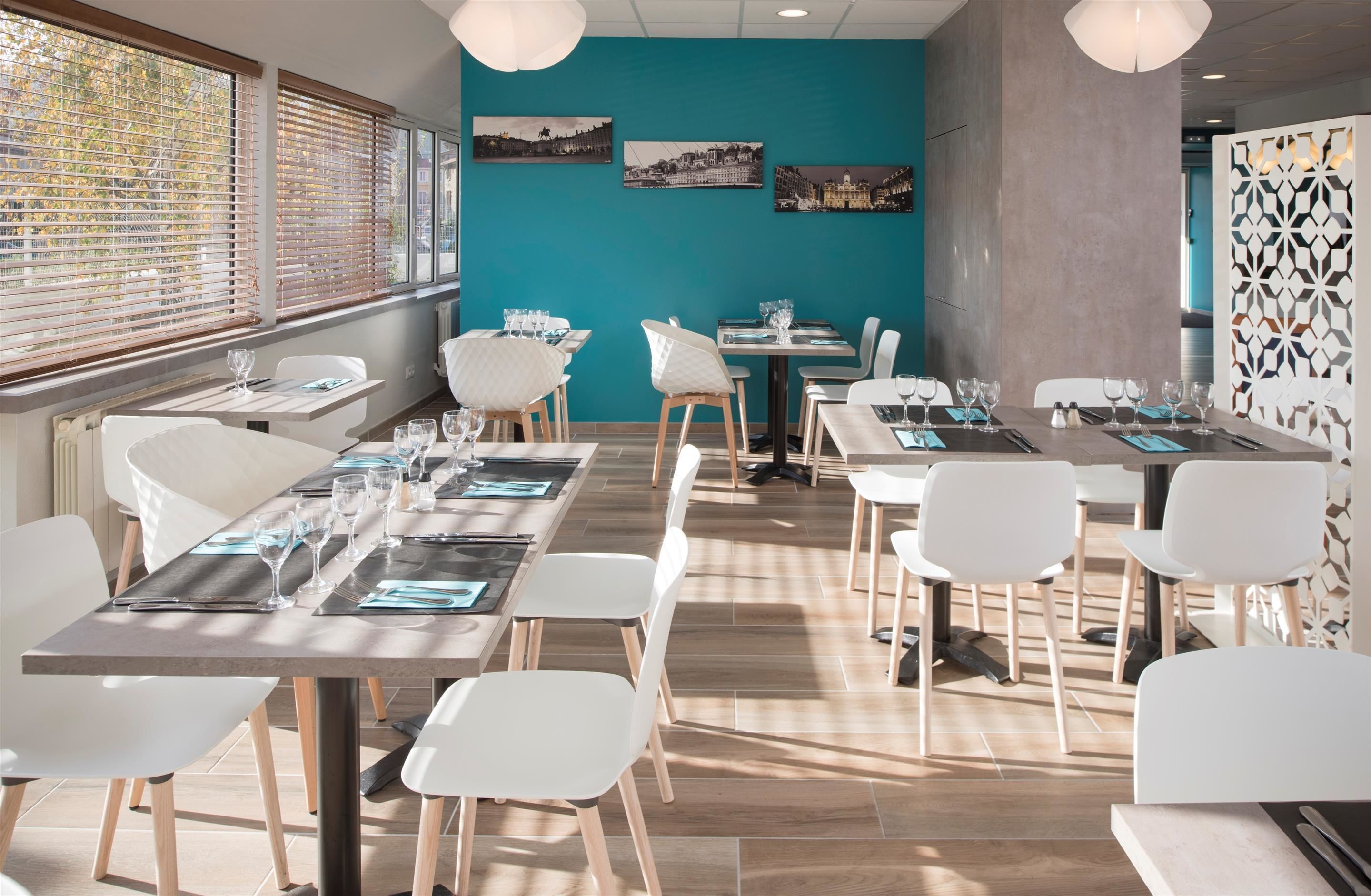 A modern dining area with long tables, white chairs, and cityscape artwork on the walls.