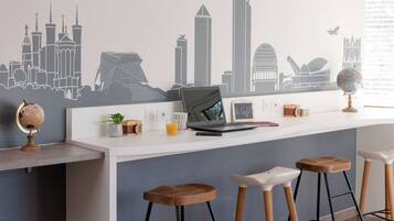 Una cucina moderna con un quadro raffigurante un panorama cittadino, un portatile, un mappamondo e sgabelli di legno.