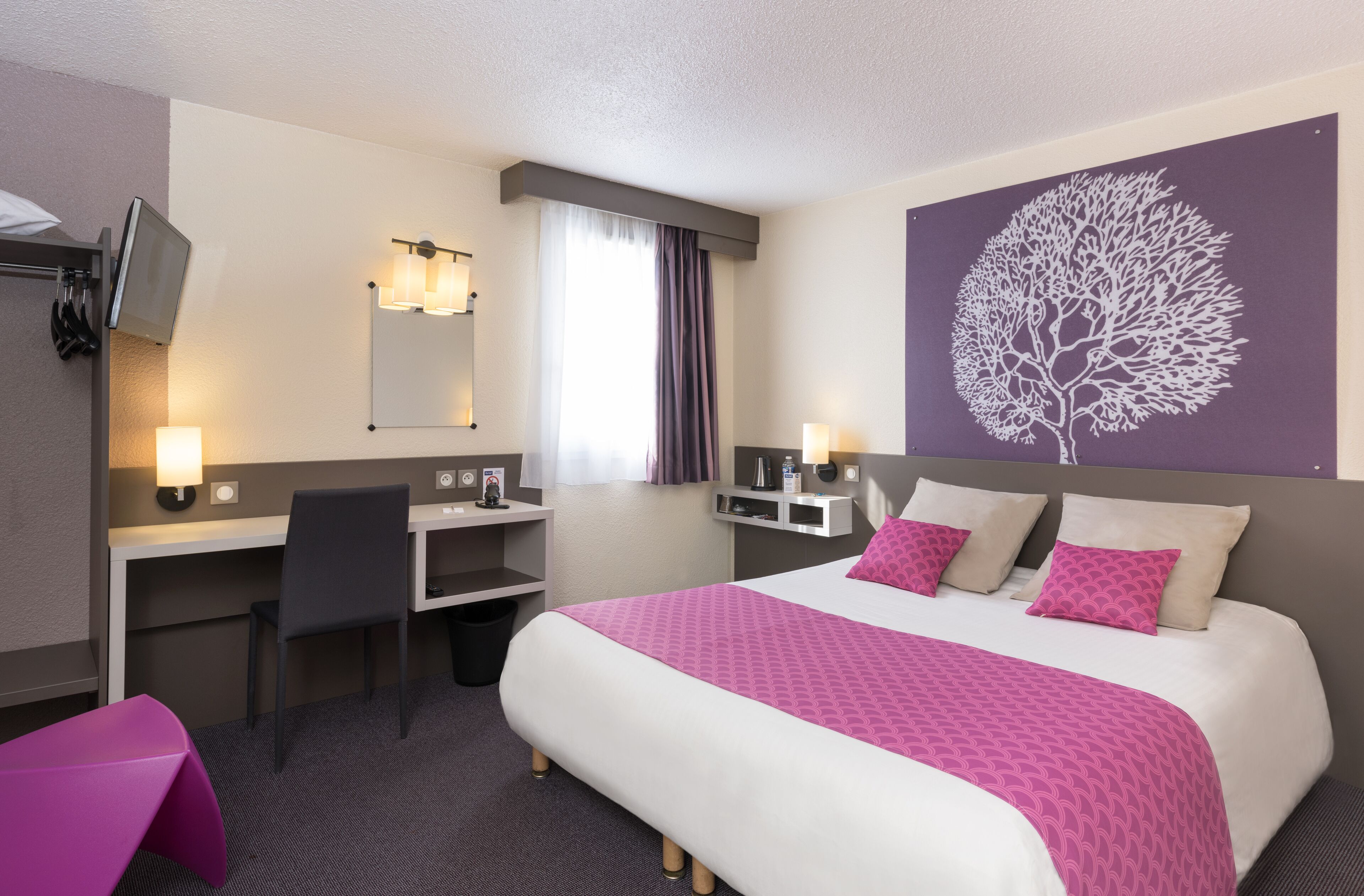 Une chambre d’hôtel équipée d’un lit, d’un bureau, d’une chaise et d’un téléviseur.