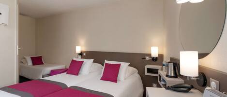 A hotel room with two beds, a desk with a telephone and a coffee maker, and a mirror on the wall.