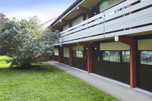 Um edifício com telhado plano, várias janelas e uma galeria coberta.