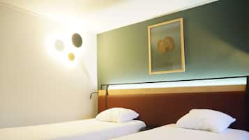 Ein Hotelzimmer mit zwei Einzelbetten, einer Wandleuchte und einem gerahmten Bild über den Betten.