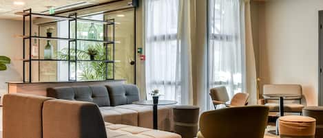 Un moderno vestíbulo con un sofá, sillas, una mesita y una estantería decorada con plantas.