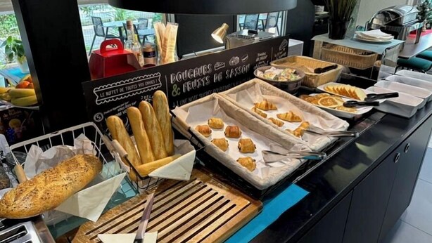 A buffet with various baked goods and pastries, including bread, croissants, and muffins.