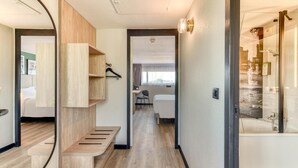 Una habitación de hotel moderna con un banco de madera, un escritorio y zona de ducha.