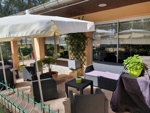 An outdoor patio area with wicker furniture, a covered seating area, and potted plants. - Campanile NATURE - Martigues (Martigues)