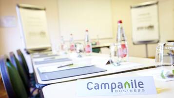 Un tavolo da conferenza con un cartello che riporta 'Campanile Business' e uno schermo per proiettore sullo sfondo.