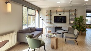 A modern living room with a sofa, chairs, a coffee table, a TV, and shelves with books and decorative items.