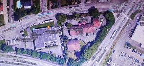 Vue aérienne d’une zone commerciale comprenant plusieurs bâtiments, notamment une concession Renault, un restaurant de pizzas et un hôtel appelé Hôtel Kyriad.
