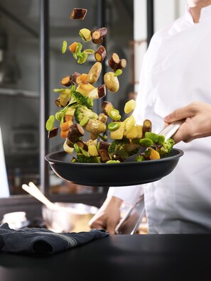 A person holding a pan with vegetables being tossed. - Campanile Salon De Provence (Salon-de-Provence)