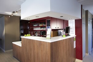 Une cuisine moderne dotée d’un îlot central en bois, d’un bar intégré et d’appareils électroménagers en acier inoxydable.