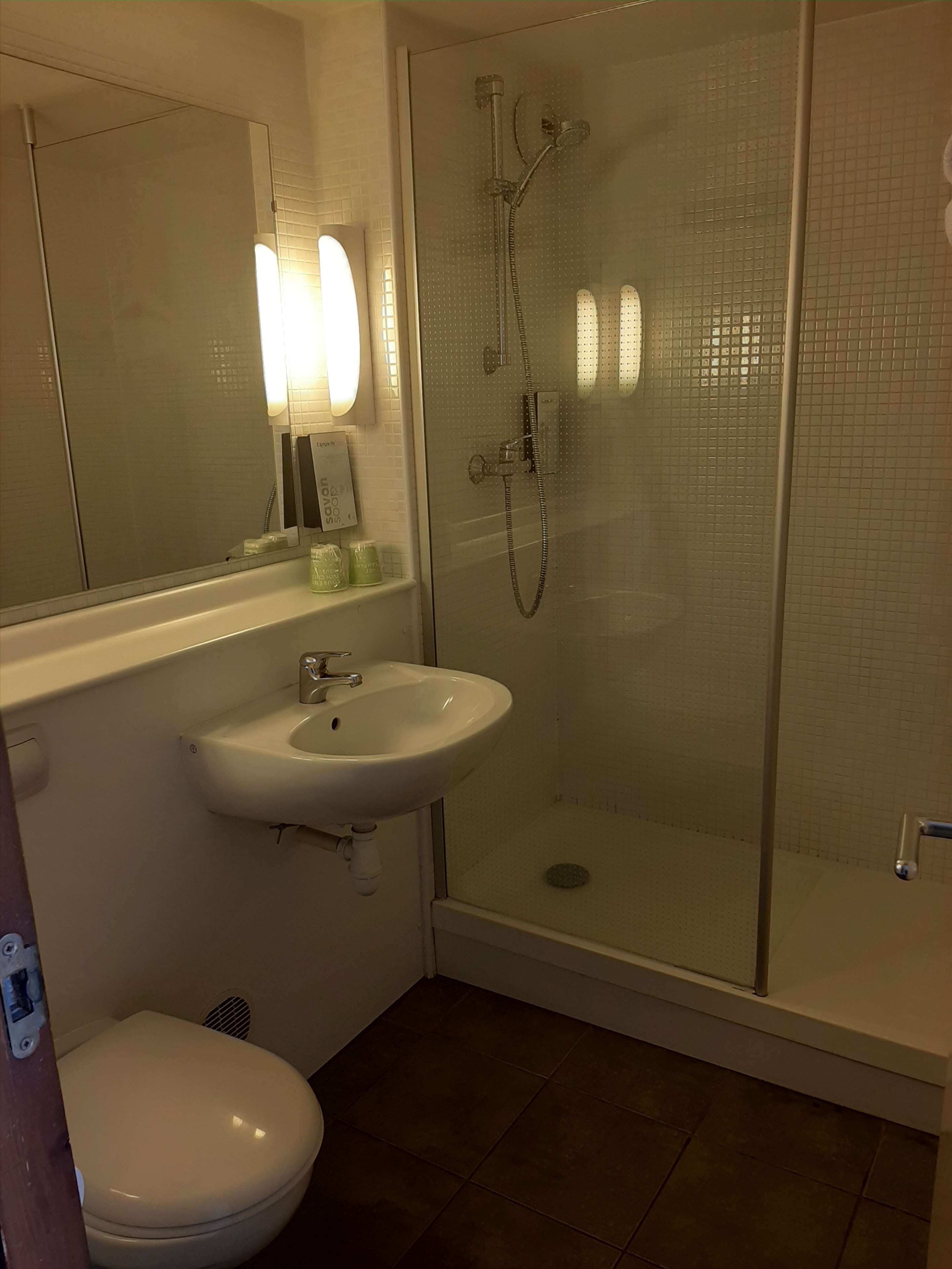 Une salle de bain équipée de toilettes, d’un lavabo et d’une douche à parois de verre.