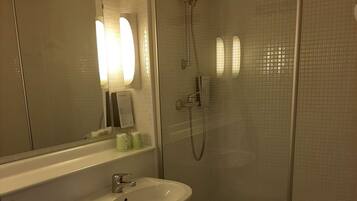 Une salle de bain équipée de toilettes, d’un lavabo et d’une douche à parois de verre.