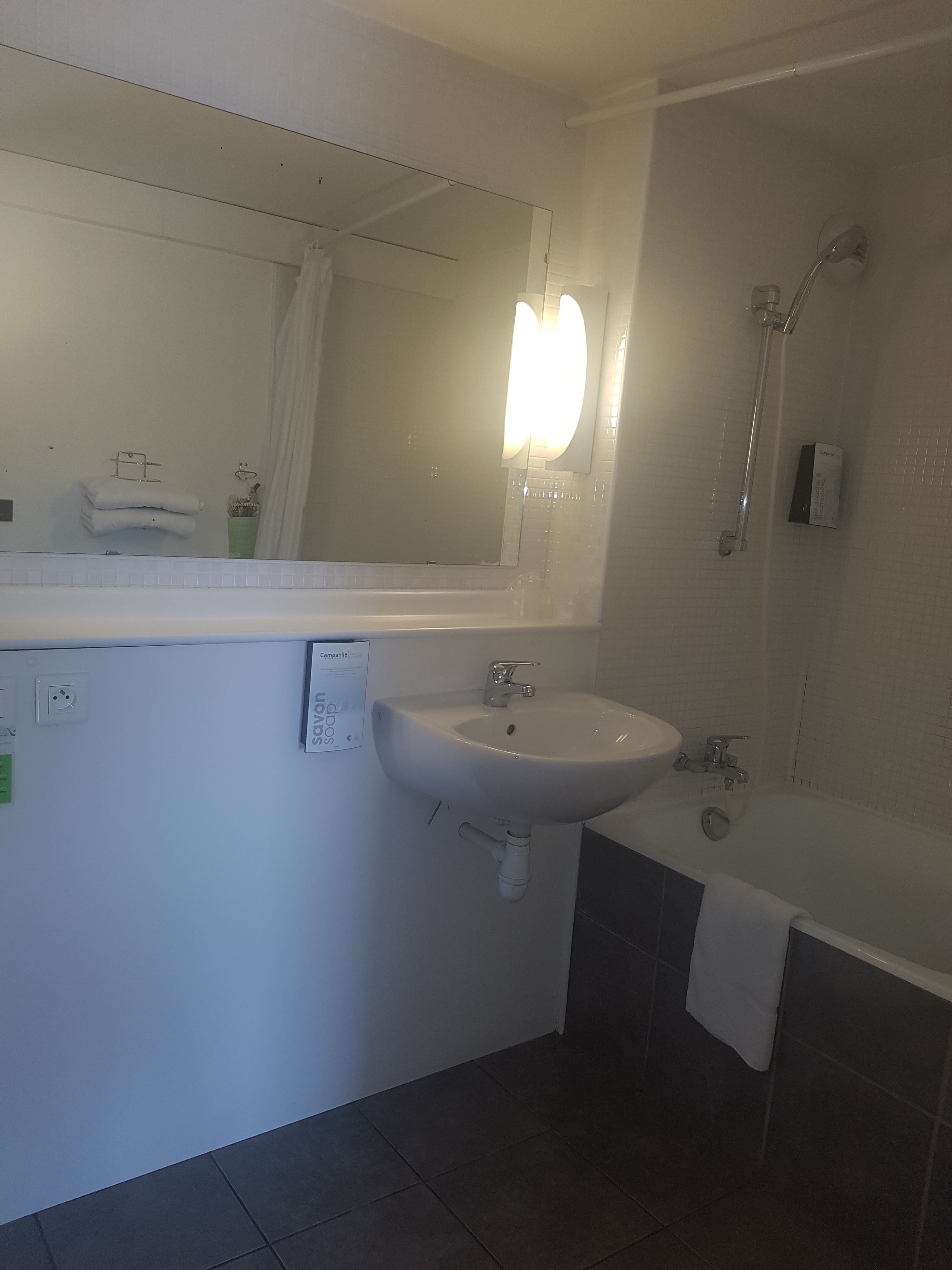 A bathroom with a sink, mirror, and shower.