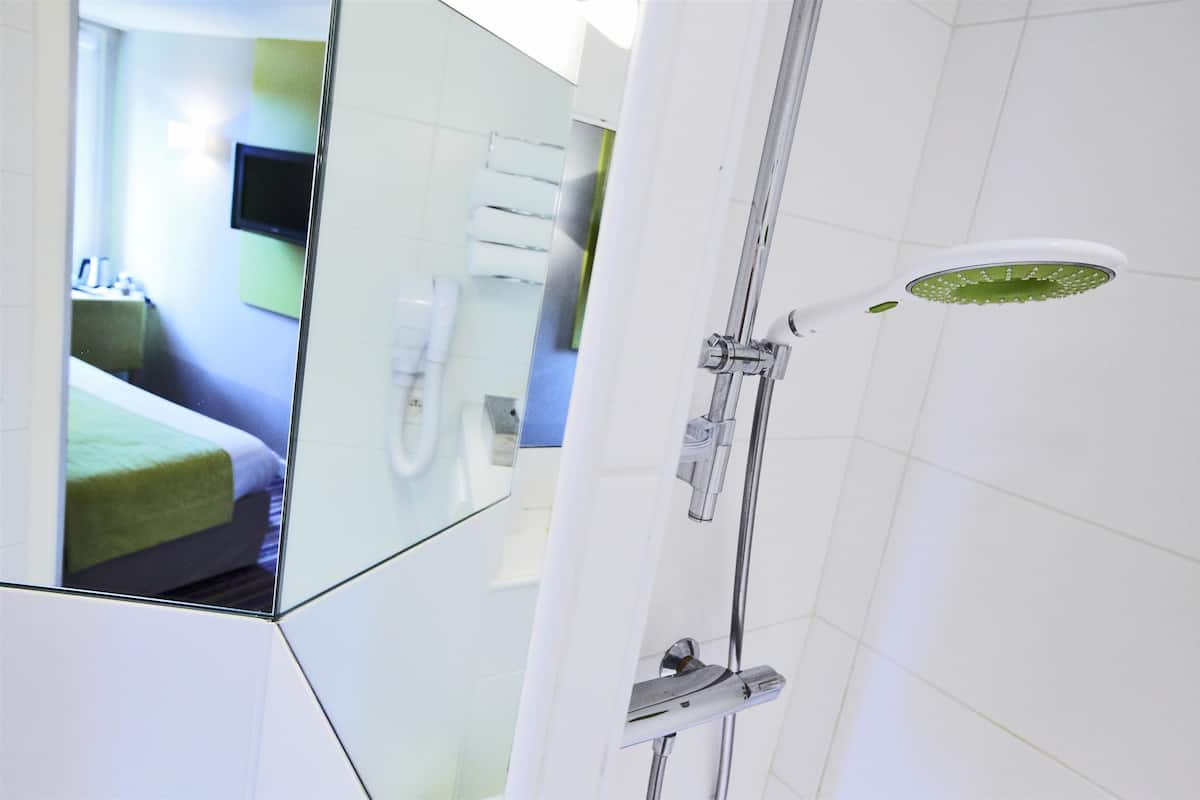 Ein modernes Badezimmer mit Duschkabine aus Glas, einem angebrachten Fernseher und einem sichtbaren Waschtisch.