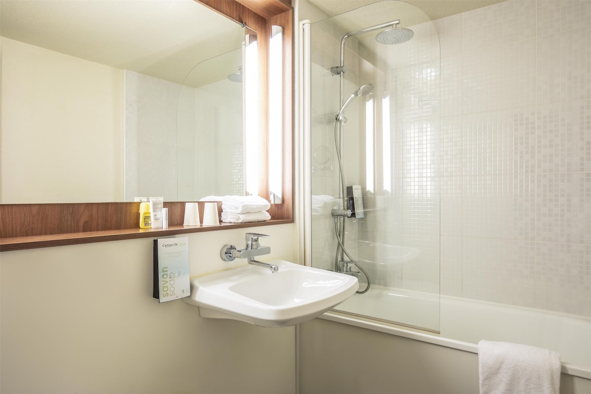 Une salle de bain avec un lavabo blanc, un miroir et une douche à parois de verre.