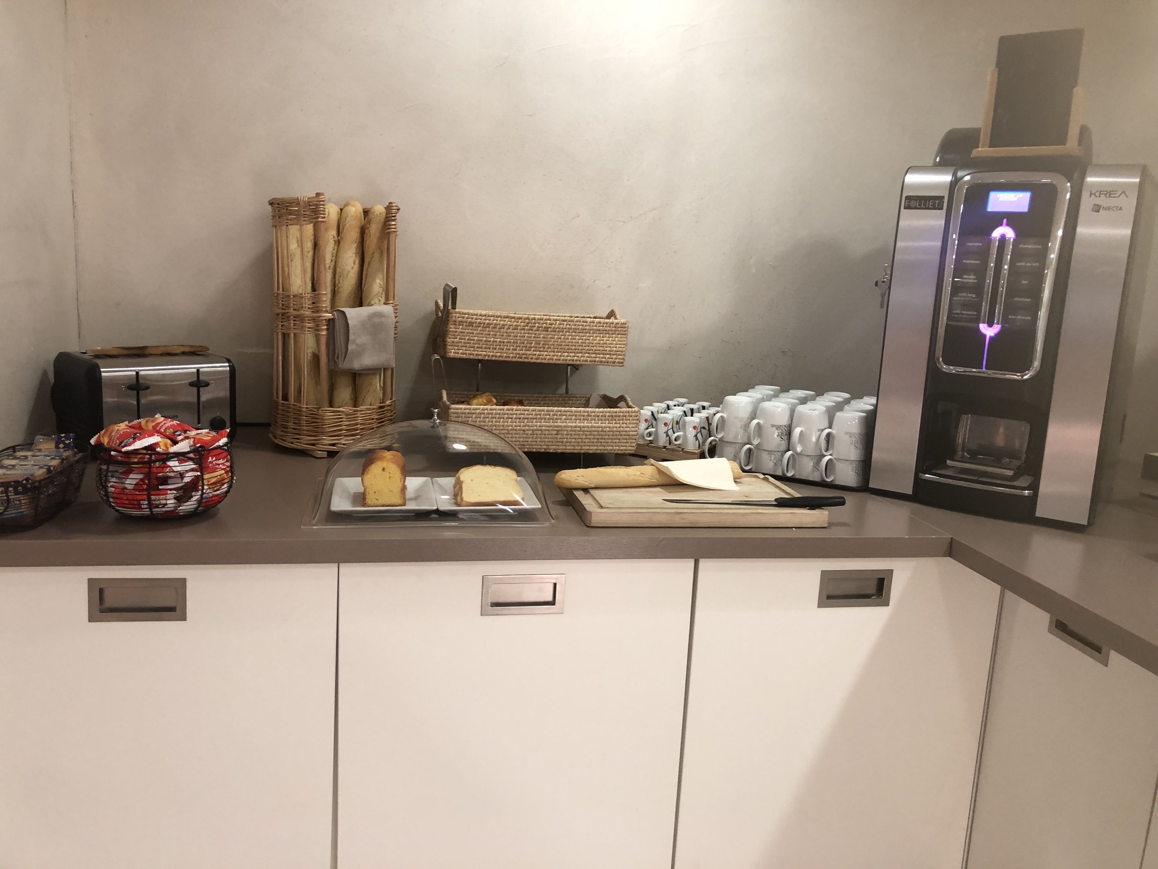 A breakfast bar with bread, pastries, and a coffee machine.