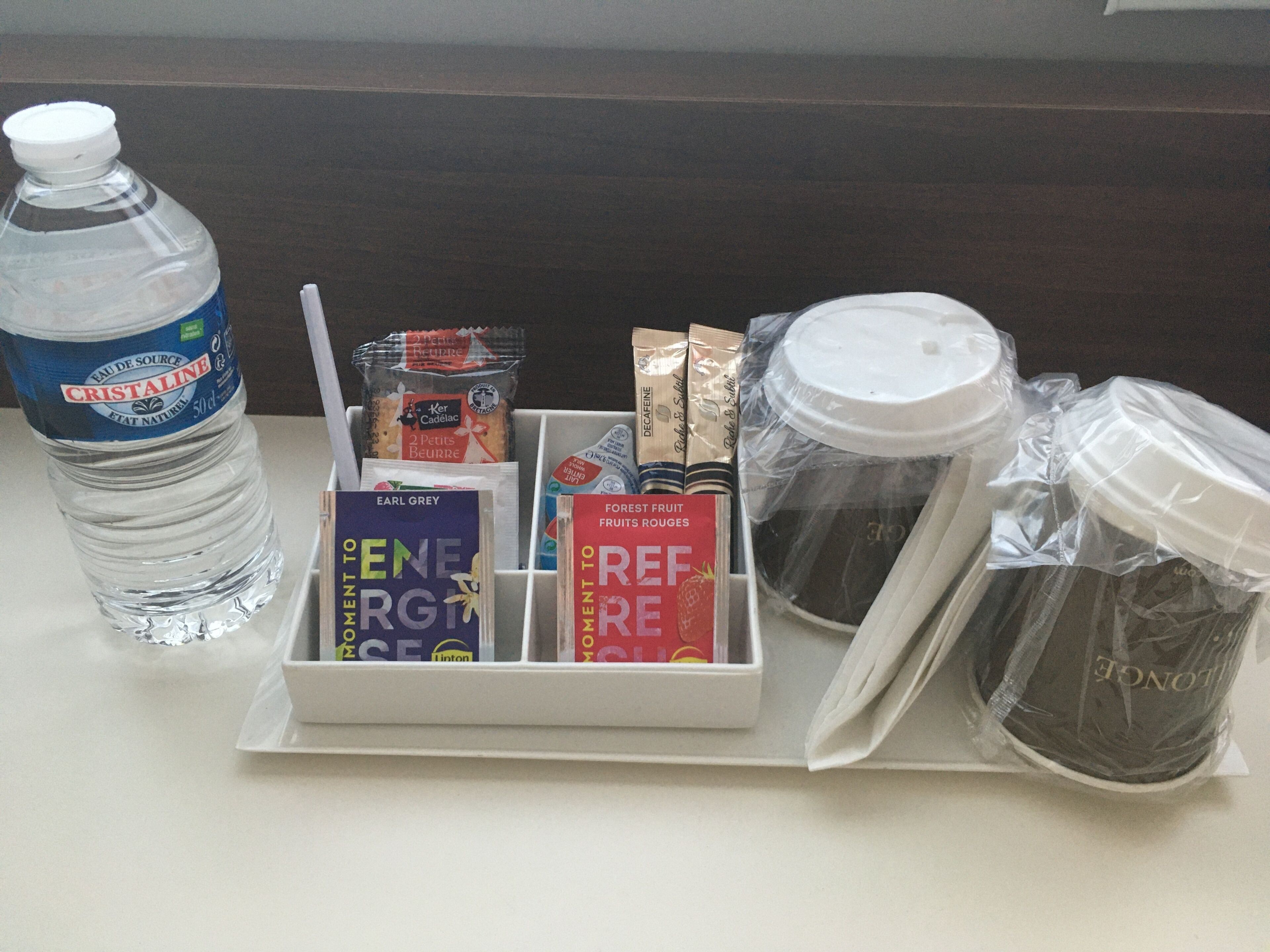 A tray with a water bottle, books, snacks, and packaged food items.