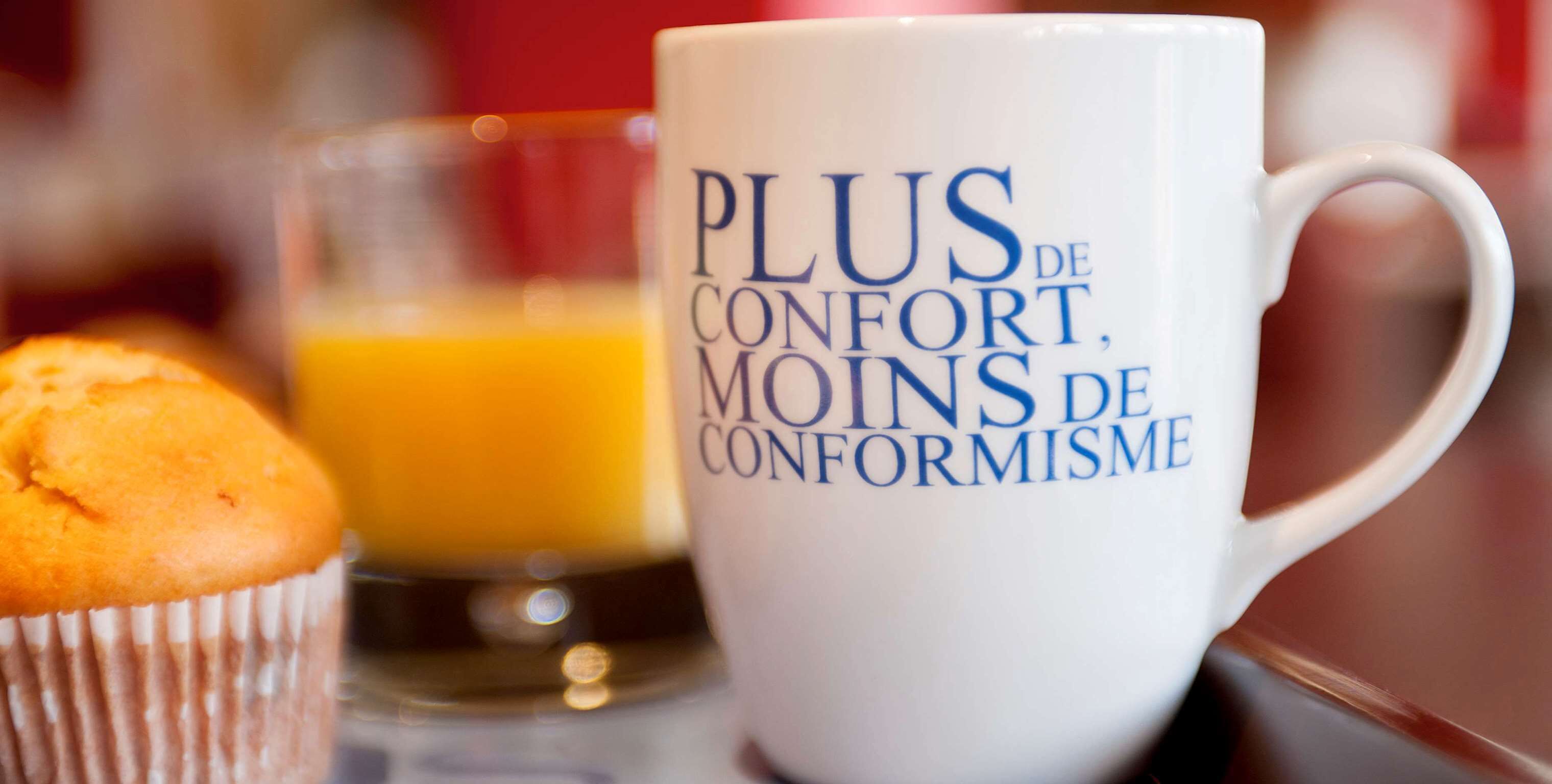 A white mug with text and a muffin on a tray.