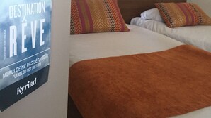 A hotel room with two beds, a world map on the wall, a lamp, and a sign with the hotel name 'Kyriad'. - Kyriad Montpellier NORD - Parc Euromédecine (Saint-Clement-de-Riviere)