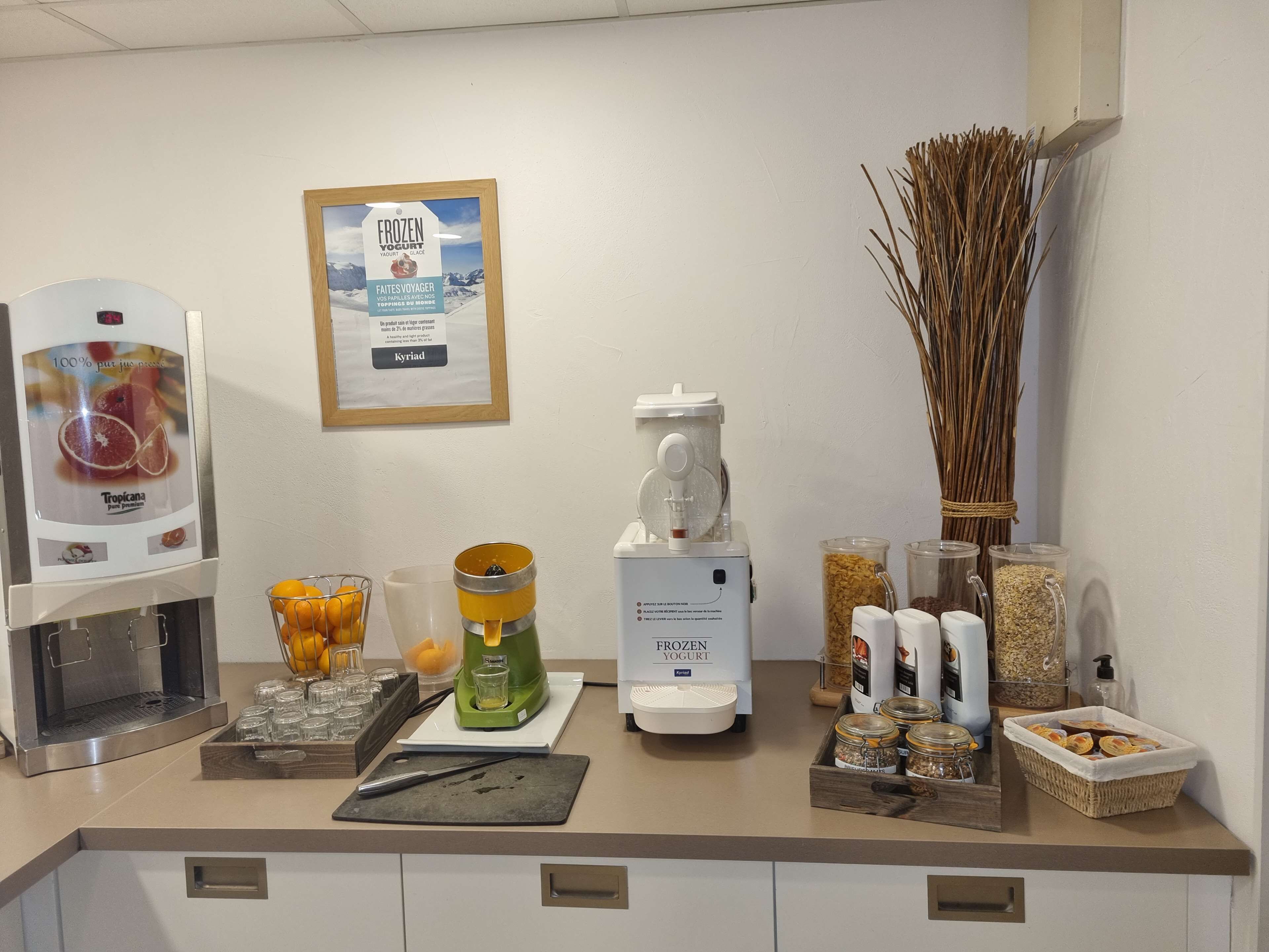 Een keukentafel met een koffiezetapparaat, een yoghurtmaker en diverse etenswaren.