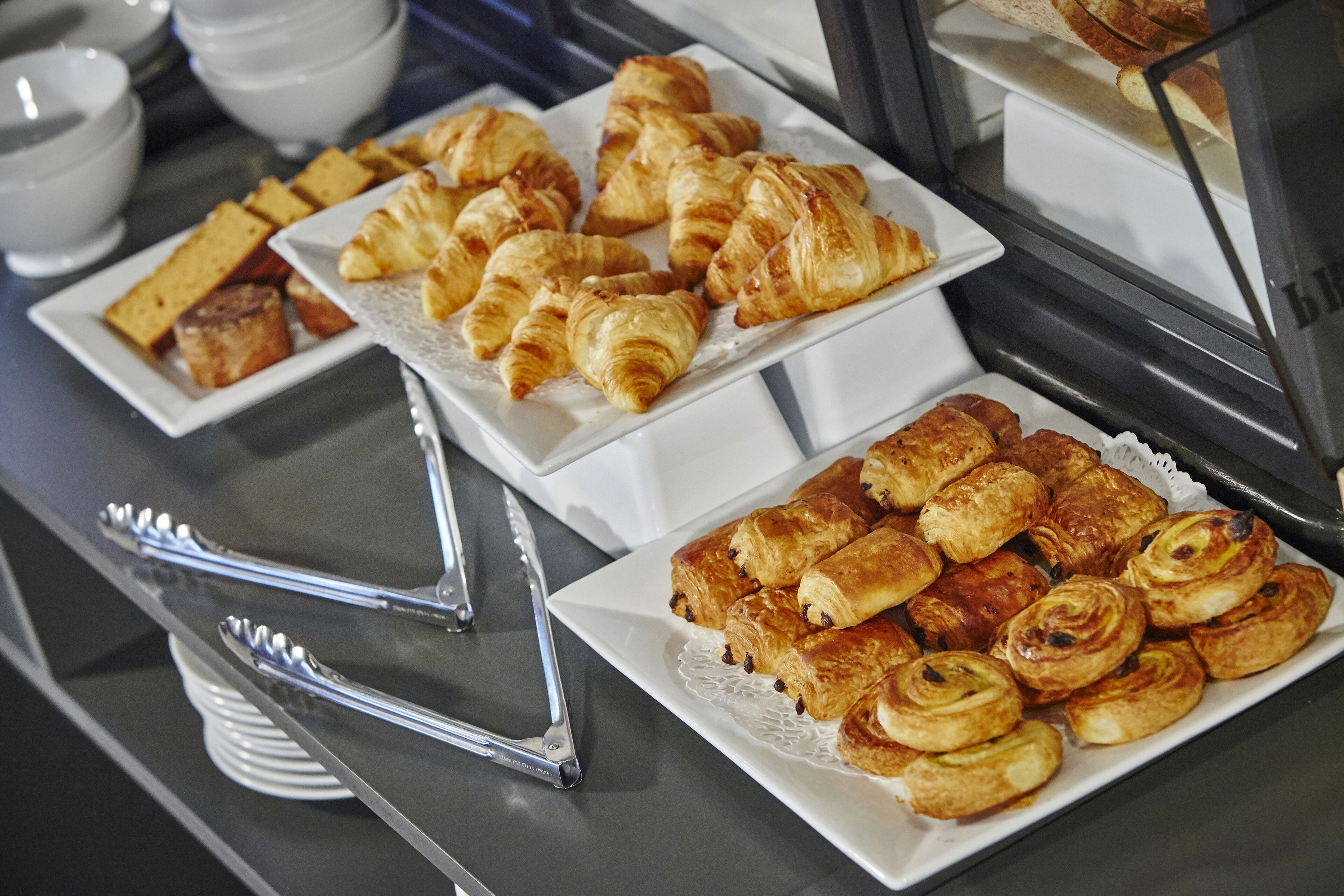 A buffet with various pastries and bread.