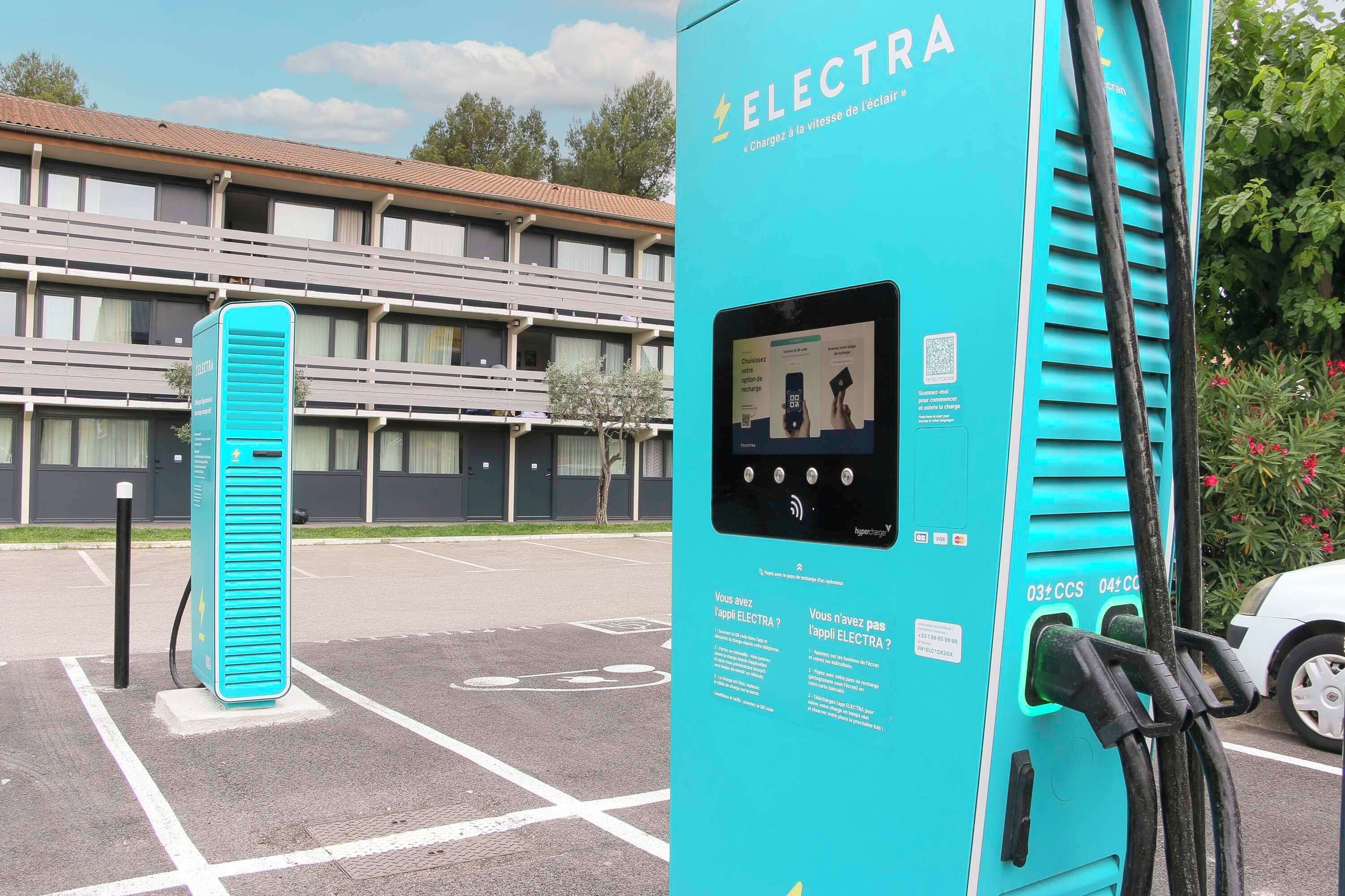 Sininen sähköautojen latausasema, jossa on digitaalinen näyttö ja latauskaapelit.
