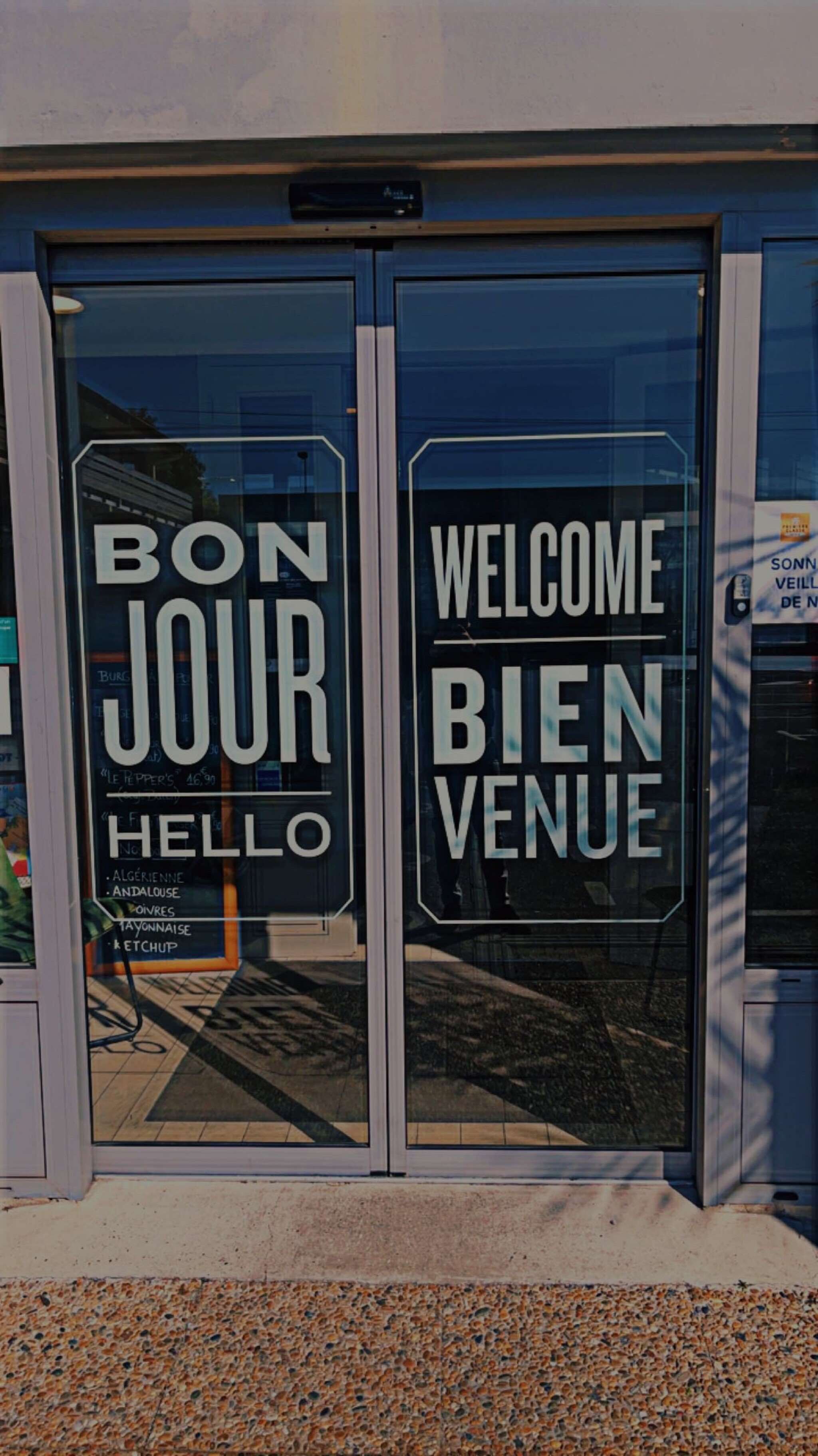 A glass door with "BON JOUR" and "WELCOME BIEN VENUE" written on it.
