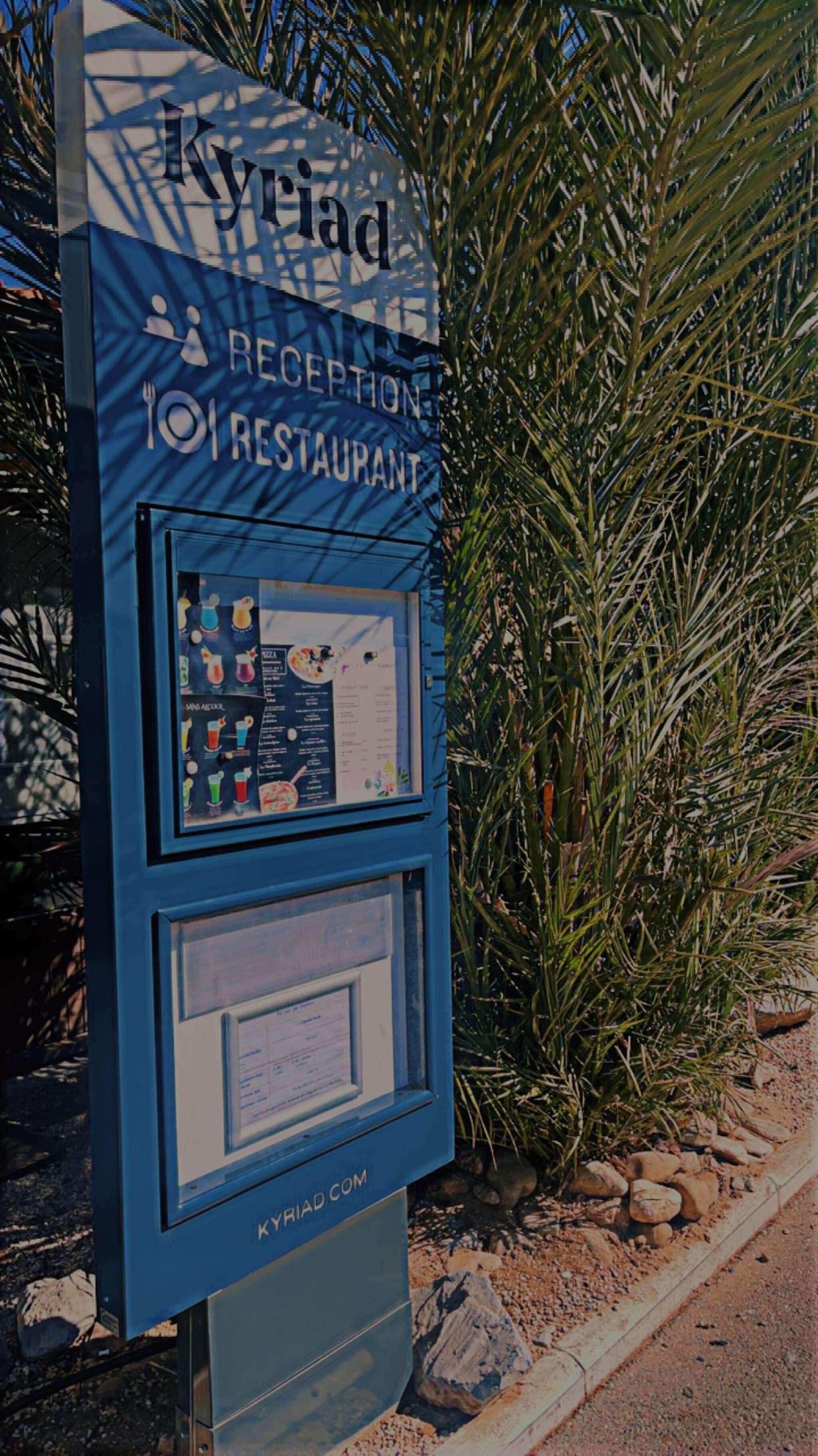 A reception kiosk with a menu board and a QR code for KYRIAD.COM.
