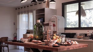 Cuina amb taula de fusta preparada per a dinar, nevera i finestra amb vista a arbres.